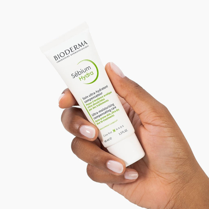 Hand holding a Bioderma Sébium Hydra skincare product on a white background